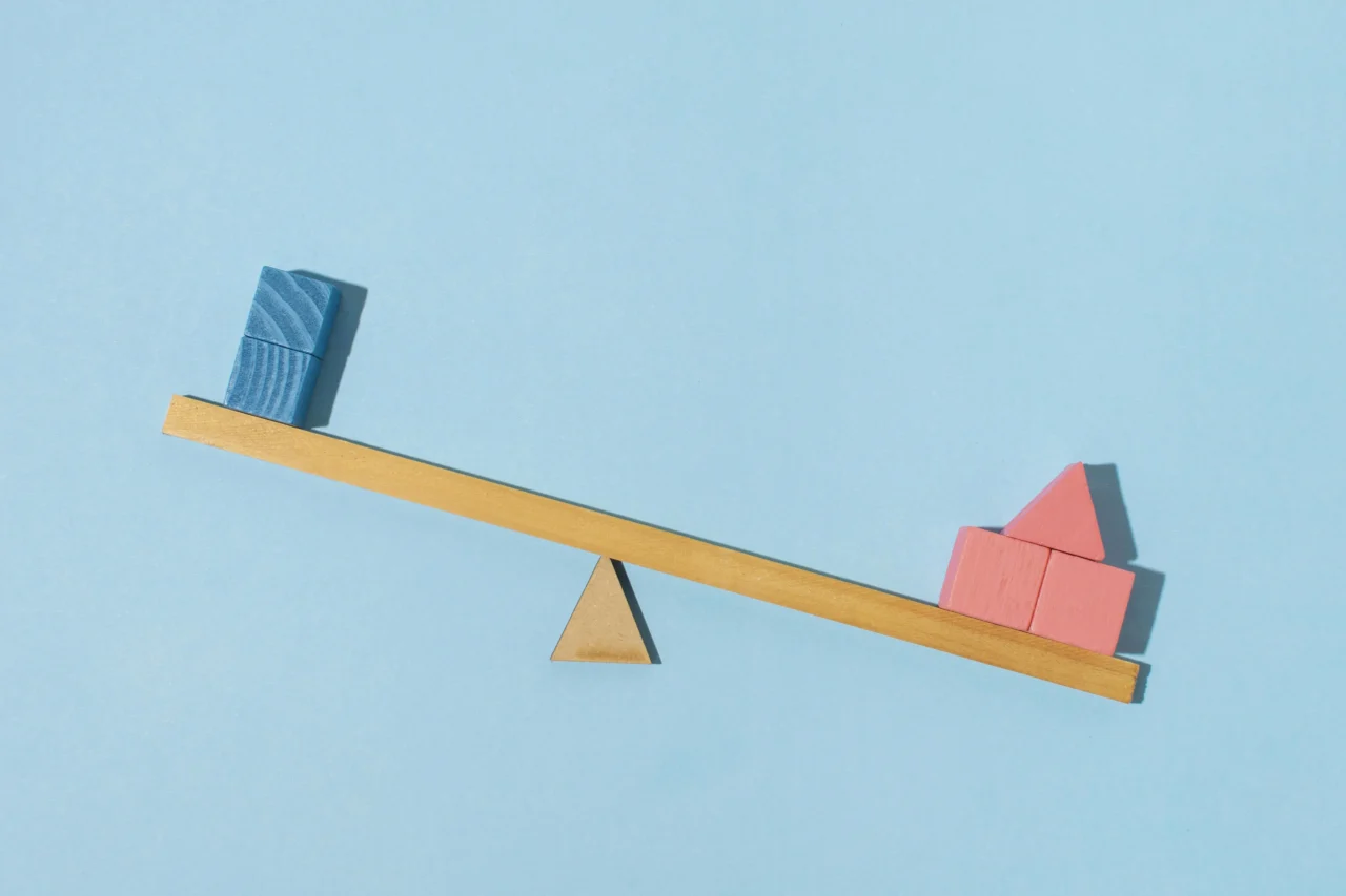 A wooden scale balancing wooden cubes.